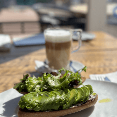 Avocado on toast on a plate in front of a coffee