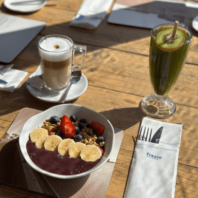 Smoothie bowl on a table surrounded by 2 drinks